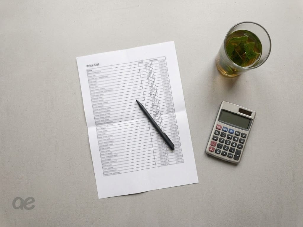 Une grille de prix, un stylo, une calculatrice et un verre de thé
